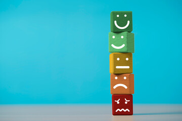 Customer evaluation concept with wooden blocks showing different facial expressions representing...