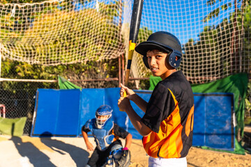 Young baseball player wearing helmet holding bat at practice