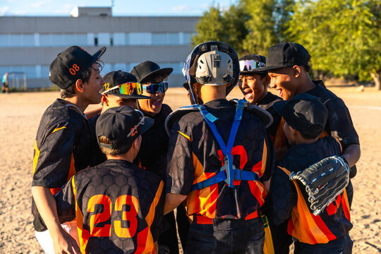 Youth baseball team huddling before game, showing teamwork - Powered by Adobe