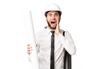Young architect man with helmet and holding blueprints over isolated chroma key background with surprise and shocked facial expression