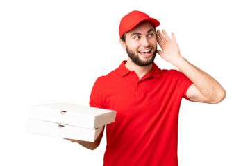 pizza delivery man with work uniform picking up pizza boxes over isolated chroma key background listening to something by putting hand on the ear