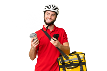 Young delivery man with thermal backpack over isolated chroma key background holding coffee to take away and a mobile while thinking something