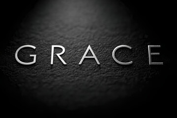 Fototapeta premium Elegant Simplicity: The word GRACE in a minimalist, light font on a textured, dark background, evoking a sense of calm and spiritual reflection.