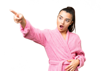 Young woman in a bathrobe over isolated chroma key background pointing away