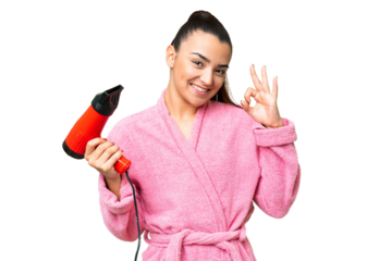 Young woman in a bathrobe holding a hairdryer over isolated chroma key background showing ok sign with fingers