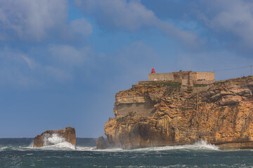 Waves breaking below the headland and the Forte de Sao Miguel Arcanjo in Nazare, Portugal.