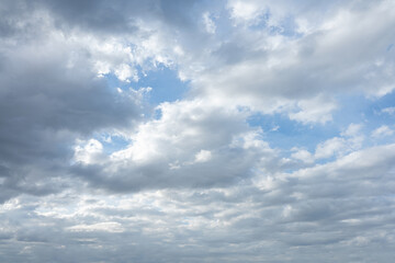 Gray and white stratocumulus clouds partially obscure patches of bright blue sky above