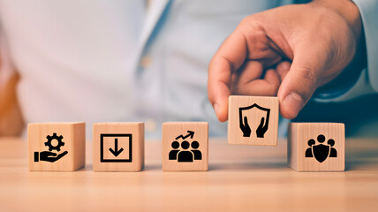 Businessman's hand placing a shield icon on a wooden block, symbolizing concepts of business protection, safety, and secure management strategies