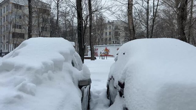 Parked cars at the street after huge snowfall in Moscow, Russia. Automobiles covered with snow. Winter concept.