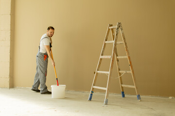 Man painting a wall with a ladder in a room during a home renovation project