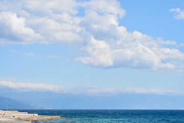 A wide view from Selce looking south across the blue Adriatic Sea with the Velebit mountain range visible in the distance under a cloudy sky.