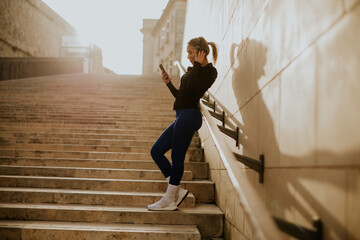 Woman enjoying a moment on stairs with her phone during golden hour
