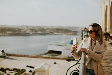 Sunshine moments in Malta by the water with a stylish woman capturing memories
