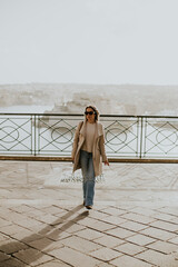 Woman walking along a scenic lookout with city skyline in the distance