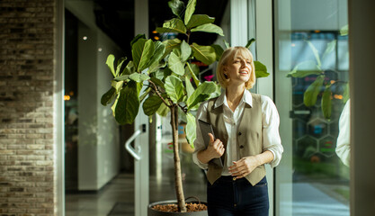 Smiling woman enjoys a sunny day indoors with a large indoor plant