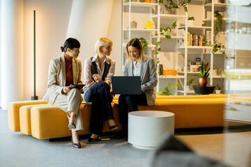 Business meeting among three women in modern office lounge during the day