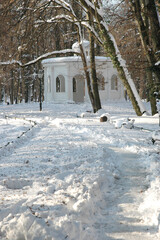 A white wooden pavilion known as the Echo Pavilion built in 1843 stands in the middle of a snowy forest in Maksimir Park during winter.