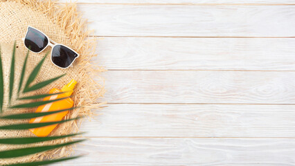 Vacation travel planning simple background of straw hat sunglasses palm leaves and sunblock lotion on white planks flat lay with copy-space