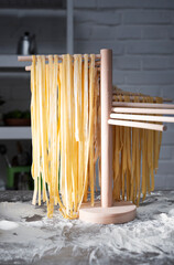 Homemade noodles hanging on wooden noodle dryer rack. Home cooking concept