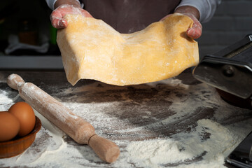 Baking concept. Caucasian female hands showing the stretched dough sheet.