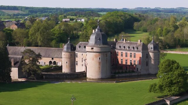 castle lavaux sainte anne or ch&acirc;teau de old building green fields water body gardens trees black domes town hills to left around right close pans aerial drone 