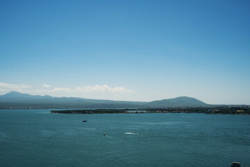 Wide panoramic view of Lake Sevan with turquoise water, small boats, and green mountain shores under a clear blue sky