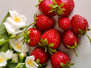 Ripe strawberries and jasmine flowers on light gray background. Copy space. Close-up