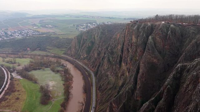 Cinematic drone orbit around the red porphyry cliffs of Rotenfels at sunset. Stunning 4K aerial footage of the rugged landscape and peaceful Nahe valley in Rhineland-Palatinate.