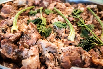 Close-up of homemade oven-baked pork knuckle pieces garnished with fresh celery, representing rustic comfort food and tradition