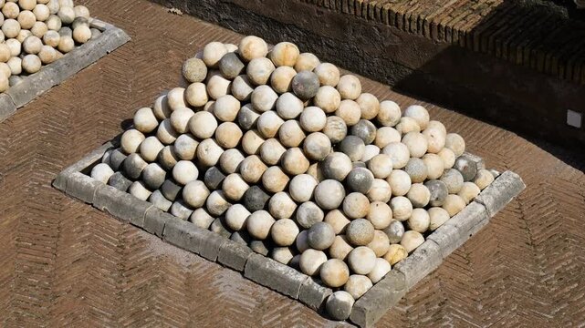 weathered stone cannonballs form precise pyramid patterned brick paving within low border military display ancient remnants historic castel sant'angelo rome italy history 
