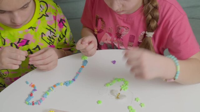 Children making colorful bead bracelets at the table