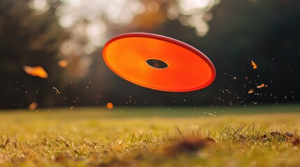 Orange frisbee flying in the air on a grassy field with trees in the background.