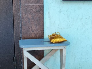 Gold pouch on wooden stool outside, a winter offering. Gift and surprise concept for gifting,...