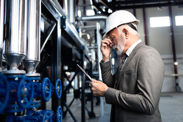 Senior engineer experiencing stress and headache in industrial plant