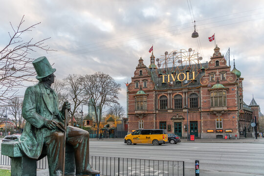 29 december 2025, Copenhagen, Denmark. Statue of Hans Christian Andersen looking at H.C. Andersen Castle at Tivoli garden in background. Cold winter day, atmospheric decorative lighting is on.