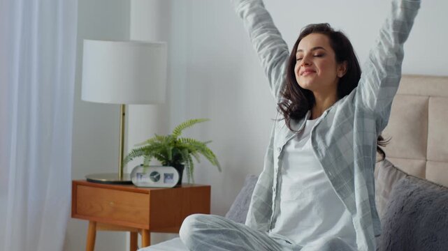 Happy smiling Caucasian woman stretching yoga in comfortable bed meditating in lotus position stretch smile in bedroom cheerful carefree female girl peaceful self care routine awaking wake up lady