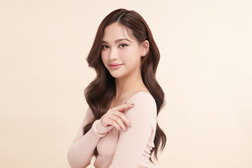 Obraz premium A beautiful young Asian woman with clean, fresh skin against a beige background. Skincare, facial treatment, cosmetology, beauty, and spa. An elegant portrait of an Asian woman.
