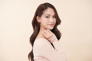 Fototapeta premium A beautiful young Asian woman with clean, fresh skin against a beige background. Skincare, facial treatment, cosmetology, beauty, and spa. An elegant portrait of an Asian woman.