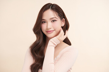 Obraz premium A beautiful young Asian woman with clean, fresh skin against a beige background. Skincare, facial treatment, cosmetology, beauty, and spa. An elegant portrait of an Asian woman.