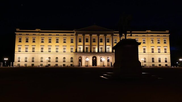 warmly illuminated neoclassical facade stretches behind dark equestrian statue grand entrance glows beneath deep black sky royal palace oslo wide norway nighttime lighting architecture 