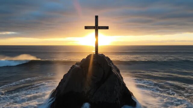 Silhouette of wooden cross on sea rock during golden sunset with crashing ocean waves