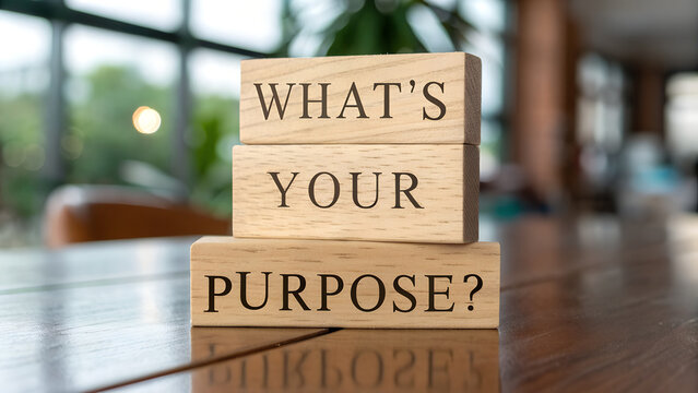 Wooden blocks stacked on a table asking the question whats your purpose in a bright indoor setting