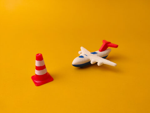 The image features a toy airplane and a mini traffic cone