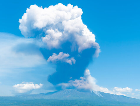 great volcano erupting on blue cloudy sky background. Vulcano Etna during eruprtion with big cloud of vulcanic smoke above the crater.