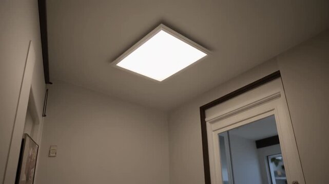 Modern square ceiling light fixture illuminating a room.