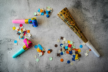 Party whistles, horns and confetti on neutral background
