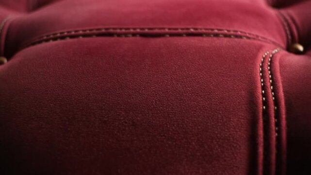 Close-up view of red velvet furniture showcasing intricate stitching details and luxurious texture