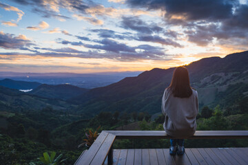 Traveler asian woman relax on balcony in homestay resort Doi Sakad mountain valley at sunset sky in Pua Nan Thailand Winter travel holiday vacation concept