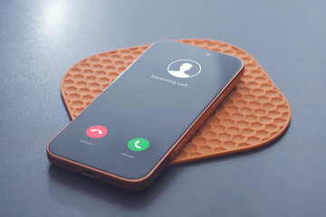 Incoming call interface displayed on modern smartphone on a table. Concept of mobile communication, phone call notification, digital contact and customer support.