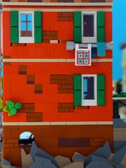 Obraz premium Tambov, Russian Federation - January 05, 2026 A close-up shot of a red two-story Lego building, featuring green shutters, white-framed windows. LEGO Ideas Italian Riviera set.